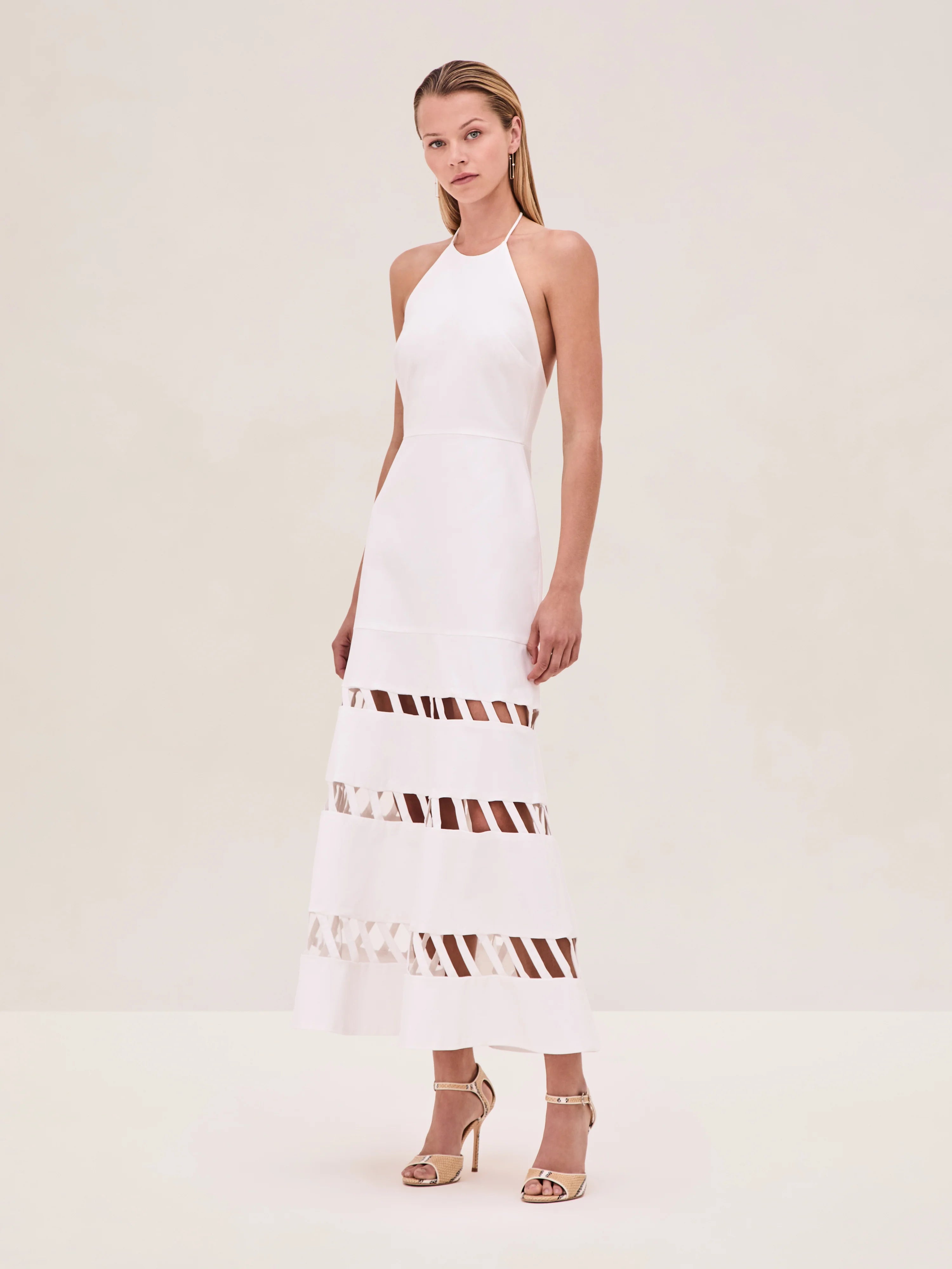 The Janessa Dress by Alexis combines classic comfort with modern detail through its breathable cotton fabric and halter neckline. Its midi length offers versatile styling options, while the distinctive cut-out ladder detailing adds an elegant touch of texture and visual interest, making it a refined choice for warm-weather occasions.