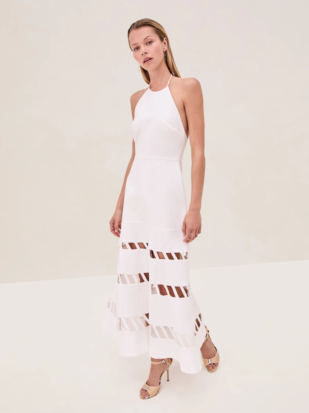 The Janessa Dress by Alexis combines classic comfort with modern detail through its breathable cotton fabric and halter neckline. Its midi length offers versatile styling options, while the distinctive cut-out ladder detailing adds an elegant touch of texture and visual interest, making it a refined choice for warm-weather occasions.