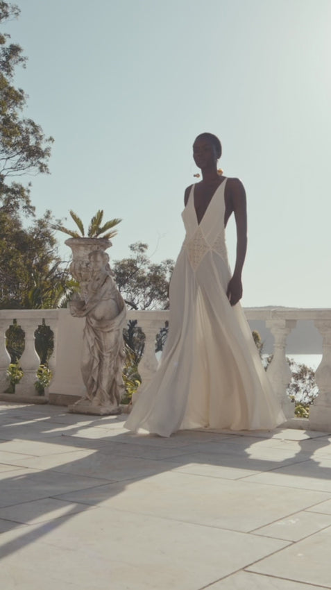 Effortlessly graceful, the Lavinia Dress captures modern elegance with a plunging V-neckline adorned with delicate lace detailing. Adjustable straps converge at an open back for a striking silhouette, while the softly ruched skirt flows with fluid movement. Crafted from lightweight georgette, this gown offers comfort and sophistication for intimate celebrations or romantic occasions.