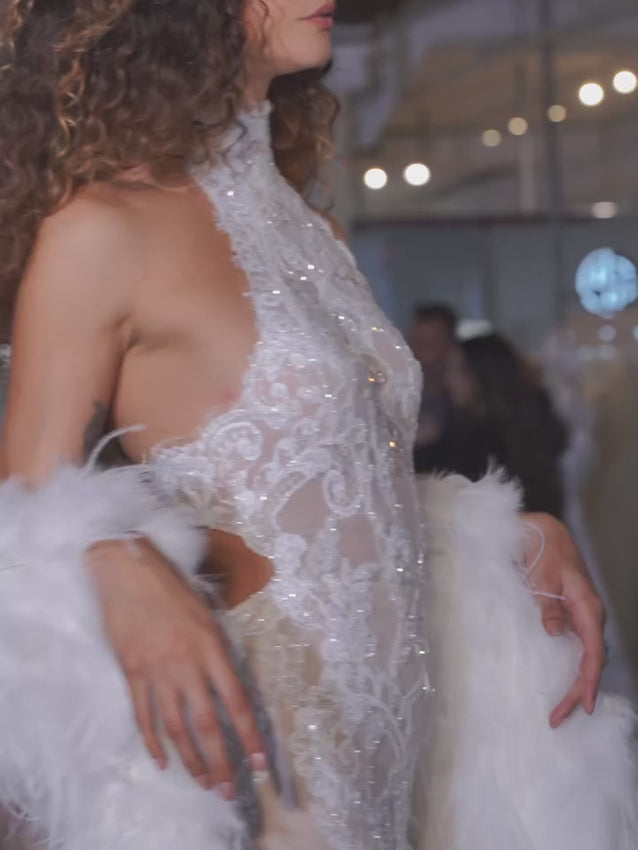 A breath-taking blend of timeless lace and modern allure, the Charlotte Gown is designed for the bride who wants tradition with a touch of bold sophistication. Featuring a high halter neckline that elongates the silhouette, this gown is crafted from intricately embroidered lace layered over a sheer, body-skimming base. The lace placement is thoughtfully patterned to contour and flatter, creating a sculpted, feminine hourglass shape from every angle.