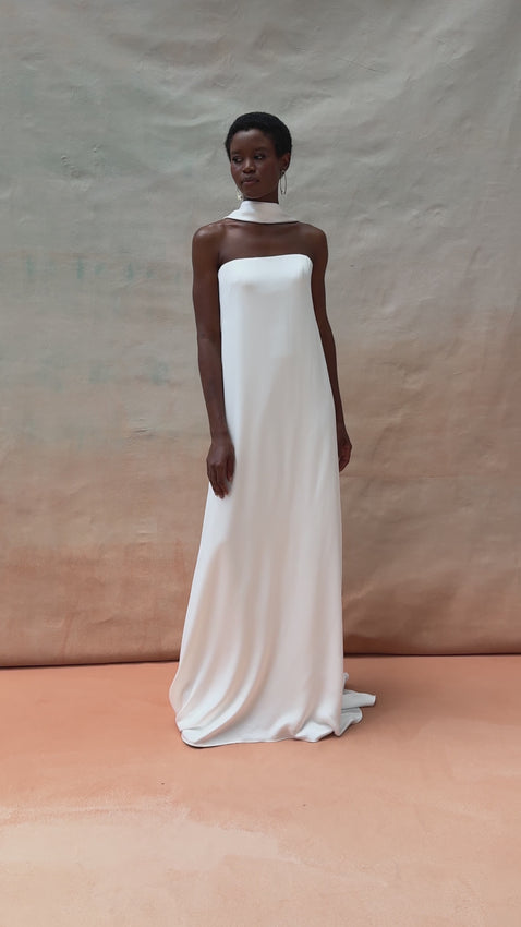 Crafted from our luminous luxe satin, the Jenny Dress combines understated elegance with striking sophistication. The clean, straight strapless neckline frames the shoulders beautifully, while the sleek sheath silhouette creates a flattering, streamlined silhouette. Structured with internal boning and bust cups for a perfect fit, this gown is fully lined for comfort and confidence. A center back zipper ensures easy wear, and delicate covered buttons trace the hem for refined detail. 
