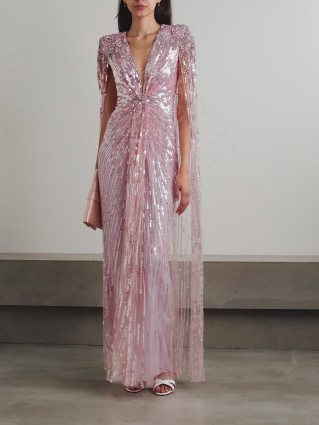 Exquisite beading, sequins, and crystals adorn the 'Gold Rush' gown, strategically placed to sculpt a defined waistline. Crafted from luxurious tulle with a daring plunge neckline and structured padded shoulders, this showstopper features a graceful cape-effect panel that drapes dramatically as you move. Lined with soft pastel-pink stretch satin for comfort and discretion.